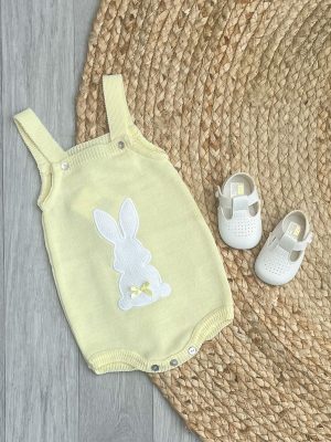 Lemon bunny romper with white bow pram shoes on a brown wicker rug.