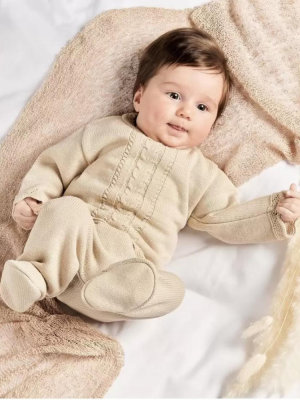 Baby laying on a neutral blanket, wearing a beige scallop knitted two piece.