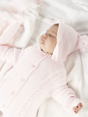 Newborn baby in a pink knitted pramsuit